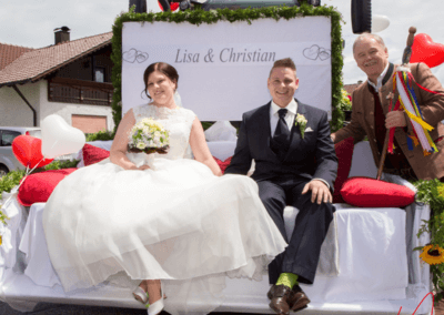 Hochzeitslader Hermann Fleischmann mit Brautpaar auf Traktor beim Hochzeitszug